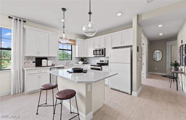kitchen with a kitchen bar, a center island, white cabinets, backsplash, and stainless steel appliances