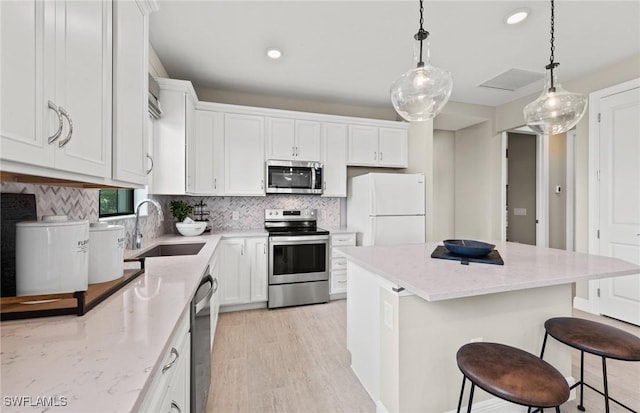 kitchen with decorative backsplash, appliances with stainless steel finishes, a center island, a sink, and white cabinetry