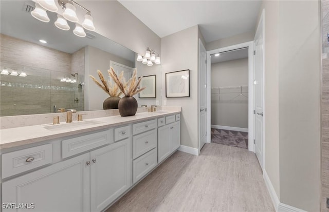 bathroom featuring wood finished floors, a sink, a stall shower, and a spacious closet