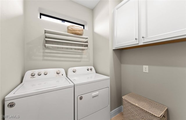 clothes washing area featuring independent washer and dryer, baseboards, and cabinet space