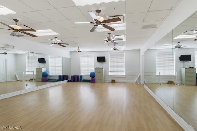 workout room featuring baseboards, a drop ceiling, and wood finished floors