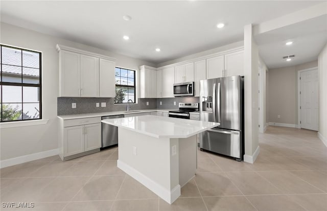 16740 Rolling Rock Blvd, Alva, FL 33920 - kitchen with appliances with stainless steel finishes, backsplash, a center island, light countertops, and light tile patterned floors