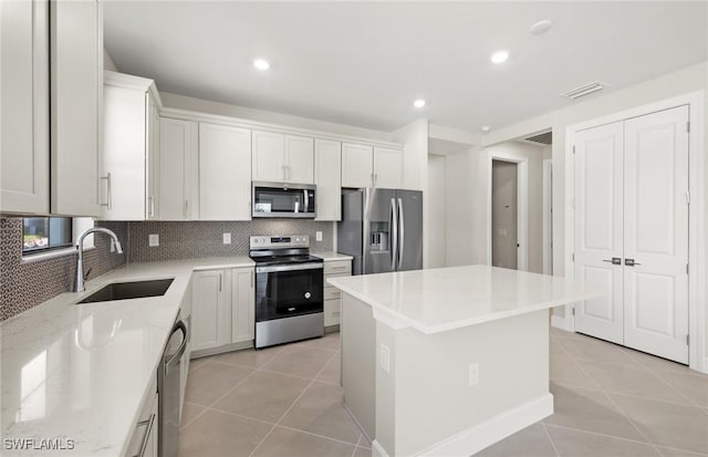 16740 Rolling Rock Blvd, Alva, FL 33920 - kitchen featuring appliances with stainless steel finishes, a sink, light tile patterned flooring, a kitchen island, and decorative backsplash