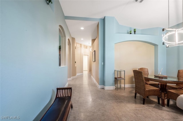 hallway with tile patterned flooring, arched walkways, recessed lighting, and baseboards