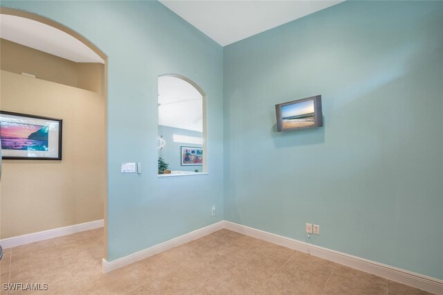 unfurnished room featuring tile patterned flooring, baseboards, and vaulted ceiling