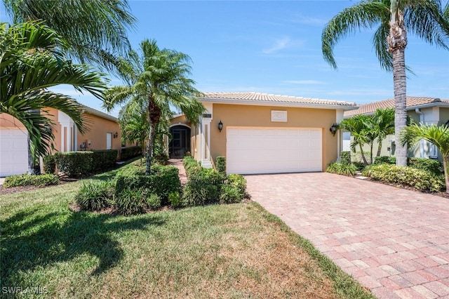 view of front of property with stucco siding, an attached garage, decorative driveway, a tile roof, and a front lawn