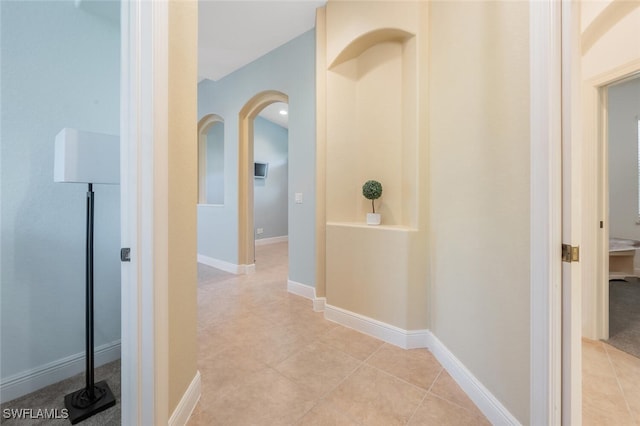 corridor featuring light tile patterned floors and arched walkways
