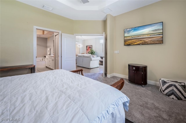 carpeted bedroom featuring ensuite bathroom and baseboards