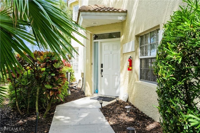entrance to property featuring stucco siding and a tile roof