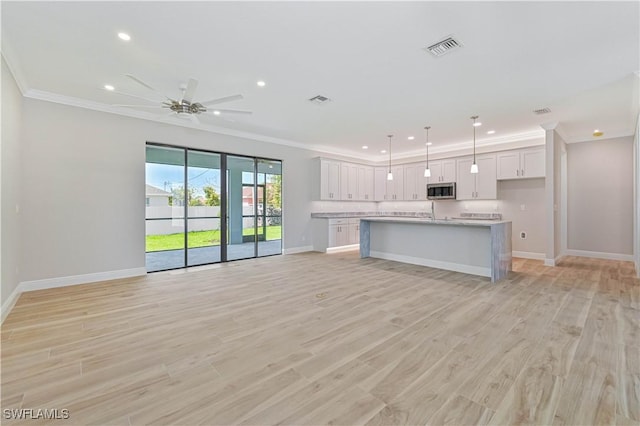kitchen featuring crown molding, visible vents, stainless steel microwave, and open floor plan