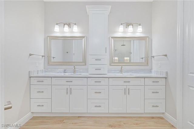 full bath featuring a sink, baseboards, a shower, and double vanity
