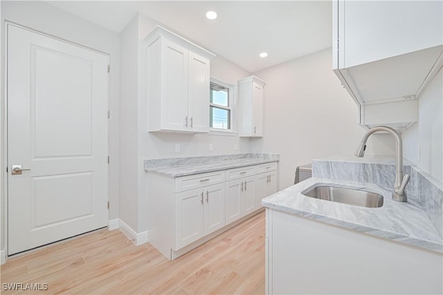 interior space featuring recessed lighting, a sink, light wood finished floors, and baseboards