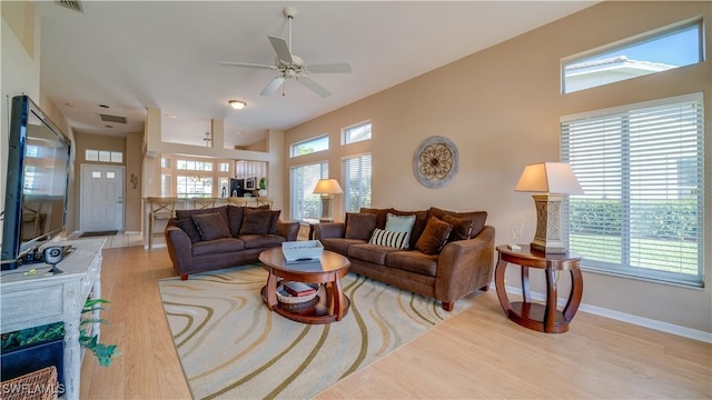 living area featuring visible vents, a towering ceiling, wood finished floors, baseboards, and a ceiling fan