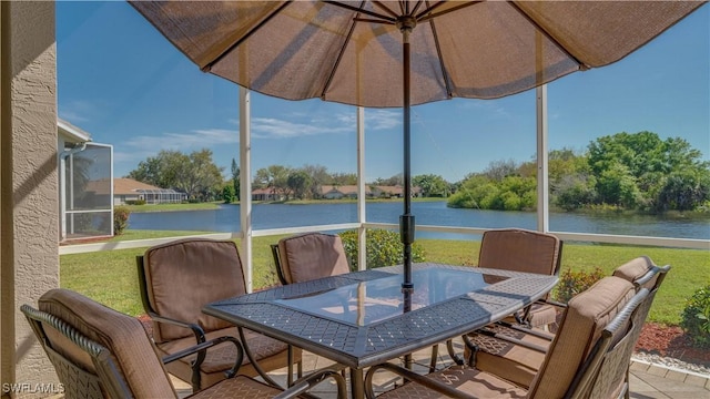sunroom / solarium with a water view and outdoor dining area