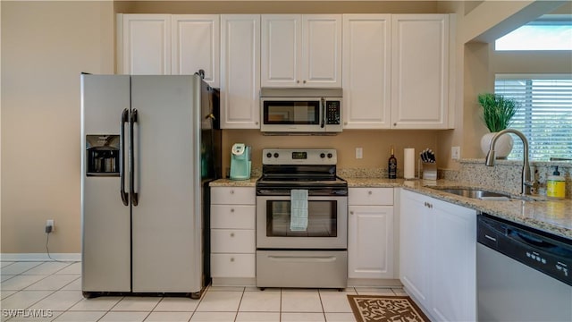 kitchen with white cabinets, stainless steel appliances, light tile patterned floors, and a sink