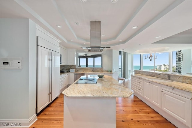 8477 Bay Colony Dr Unit 1102, Naples, FL 34108 - kitchen with a kitchen island, a sink, a raised ceiling, white cabinets, and an inviting chandelier