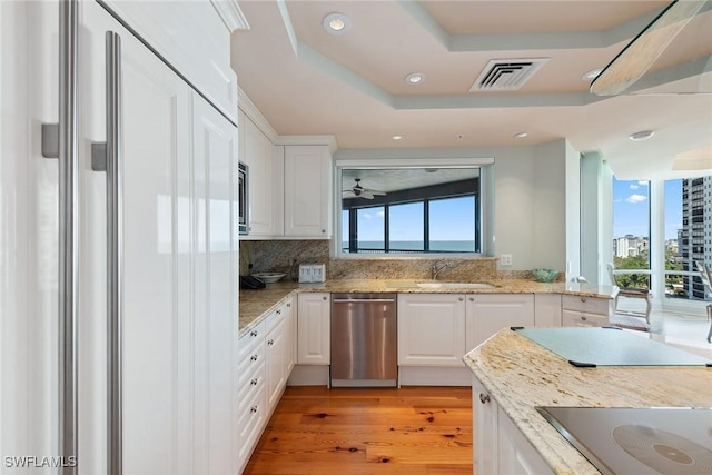 8477 Bay Colony Dr Unit 1102, Naples, FL 34108 - kitchen with stainless steel dishwasher, a sink, white cabinets, black electric stovetop, and paneled built in refrigerator