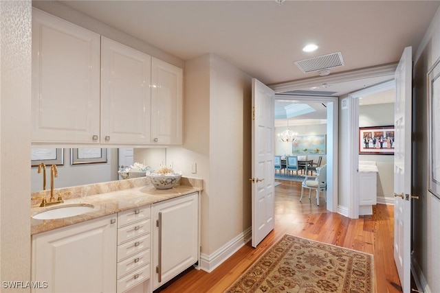 8477 Bay Colony Dr Unit 1102, Naples, FL 34108 - bar featuring light wood-type flooring, a sink, baseboards, and visible vents
