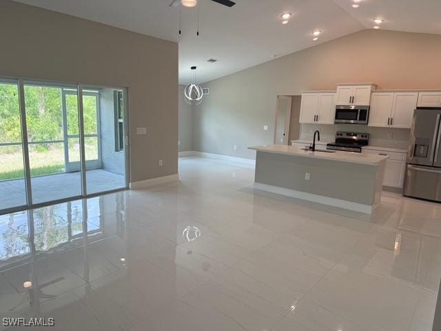 kitchen with a ceiling fan, appliances with stainless steel finishes, a sink, white cabinets, and open floor plan