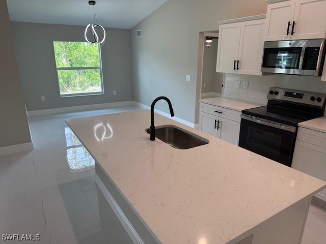 kitchen featuring white cabinets, stainless steel appliances, light stone counters, and a sink