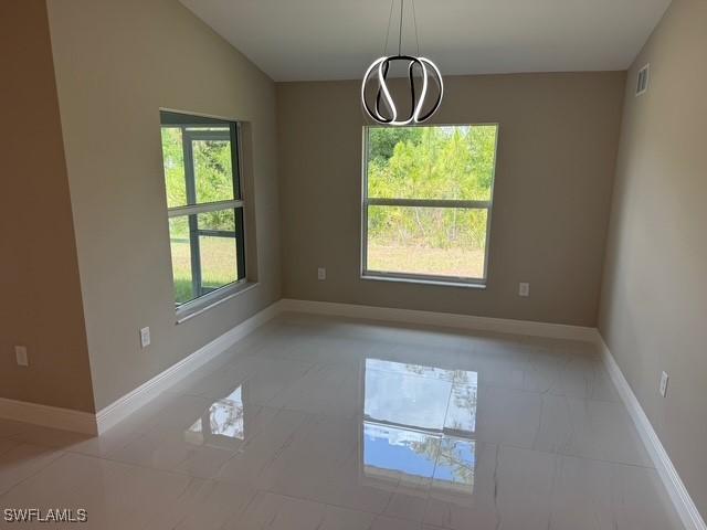 interior space with baseboards, a notable chandelier, marble finish floor, and visible vents