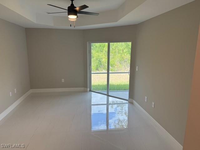 spare room featuring baseboards, a ceiling fan, and a raised ceiling