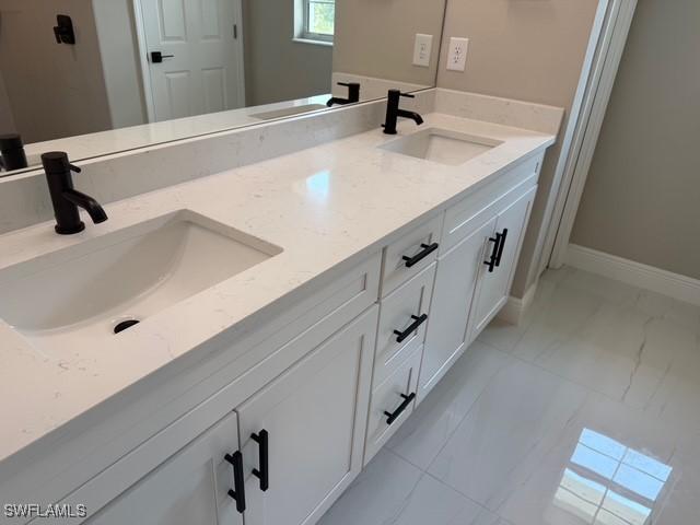 bathroom with double vanity, a sink, and marble finish floor
