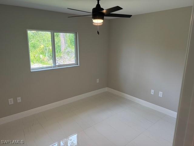 spare room with baseboards and a ceiling fan