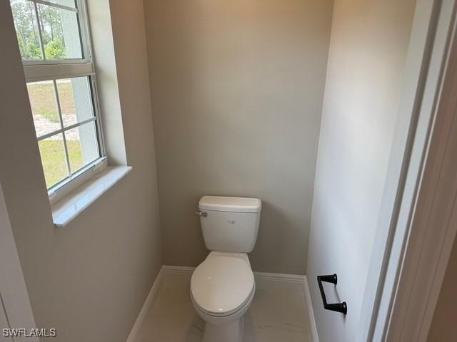 bathroom featuring baseboards, plenty of natural light, and toilet