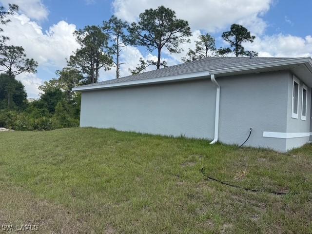 view of side of property featuring stucco siding and a yard