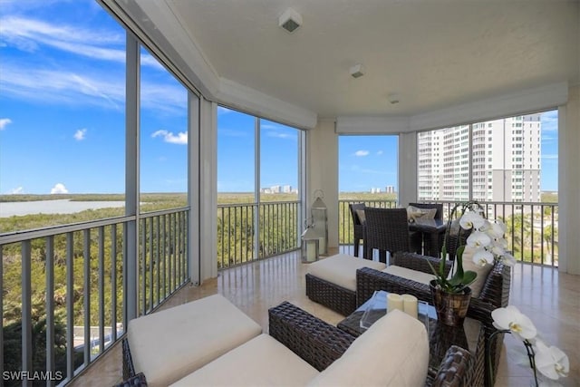 sunroom / solarium featuring expansive windows, a water view, and tile patterned flooring