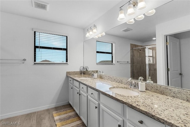 full bath featuring double vanity, visible vents, a stall shower, and a sink