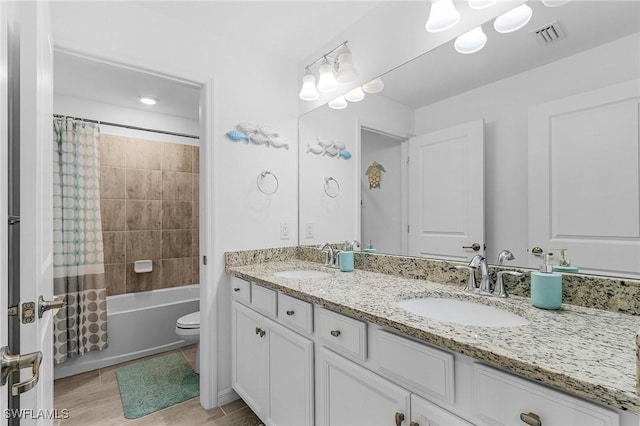 full bathroom with a sink, double vanity, toilet, and visible vents