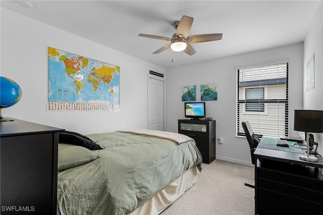 bedroom featuring ceiling fan, light carpet, a closet, and baseboards