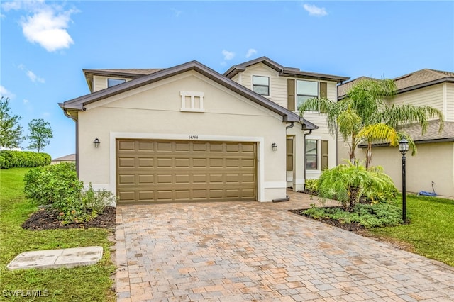 traditional-style home with a front yard, stucco siding, a garage, and decorative driveway