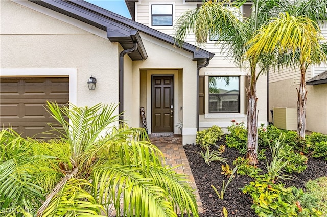 property entrance with stucco siding and a garage