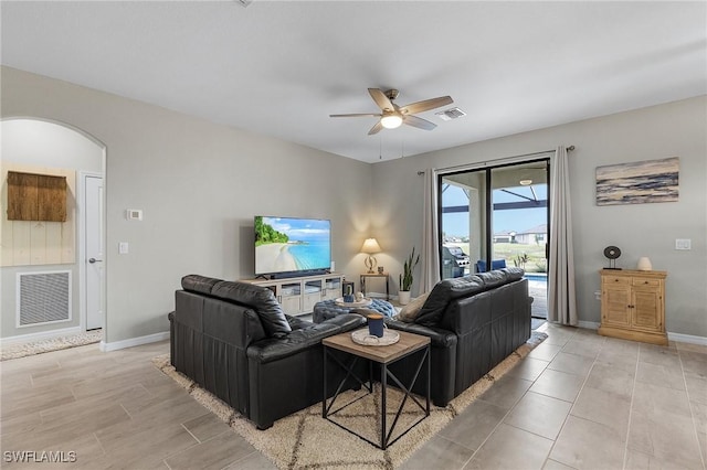 living area featuring visible vents, baseboards, ceiling fan, and arched walkways