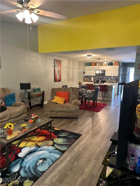 living area with a ceiling fan and wood finished floors