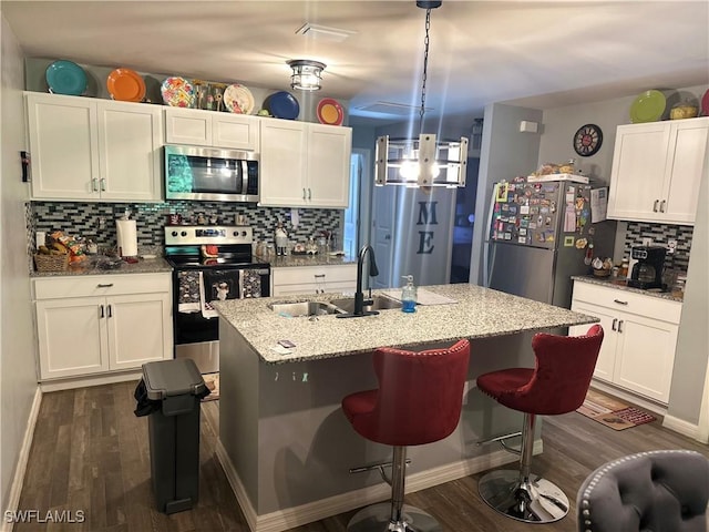 kitchen with backsplash, dark wood-style flooring, a sink, white cabinets, and stainless steel appliances
