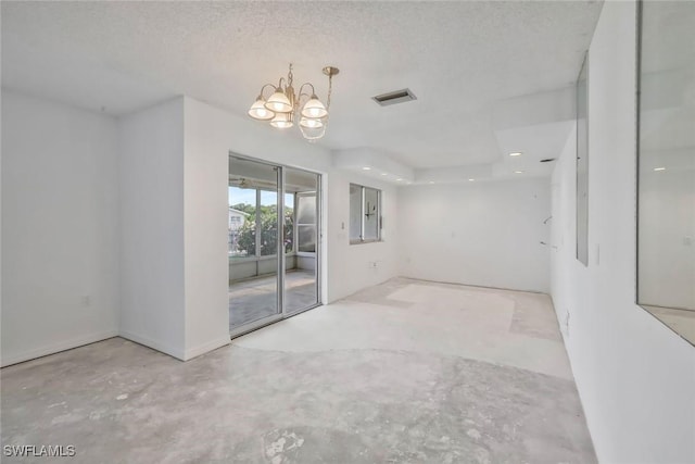 empty room featuring an inviting chandelier, a textured ceiling, concrete floors, and visible vents