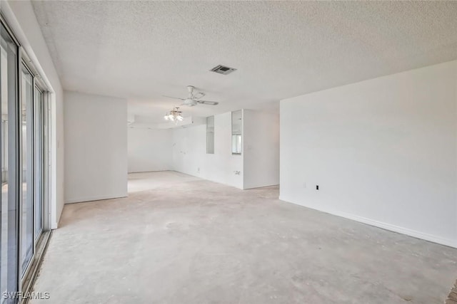 empty room featuring a wealth of natural light, concrete floors, a textured ceiling, and visible vents