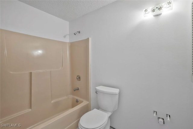 full bathroom with washtub / shower combination, toilet, and a textured ceiling