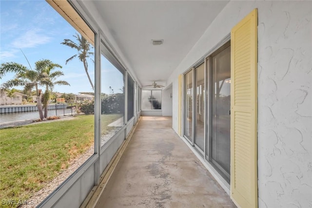 unfurnished sunroom with a water view, ceiling fan, and visible vents