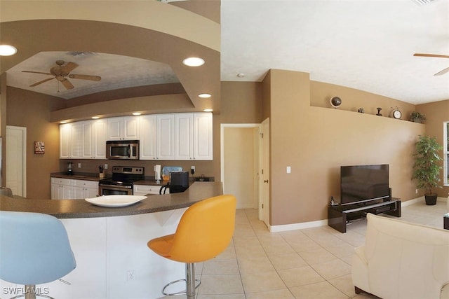 1725 SE 10th Pl, Cape Coral, FL 33990 - kitchen featuring ceiling fan, appliances with stainless steel finishes, dark countertops, a kitchen breakfast bar, and light tile patterned floors