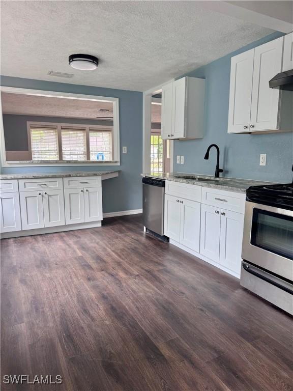 2739 Michigan Ave, Fort Myers, FL 33916 - kitchen with stainless steel appliances, a sink, dark wood-style floors, white cabinetry, and a textured ceiling