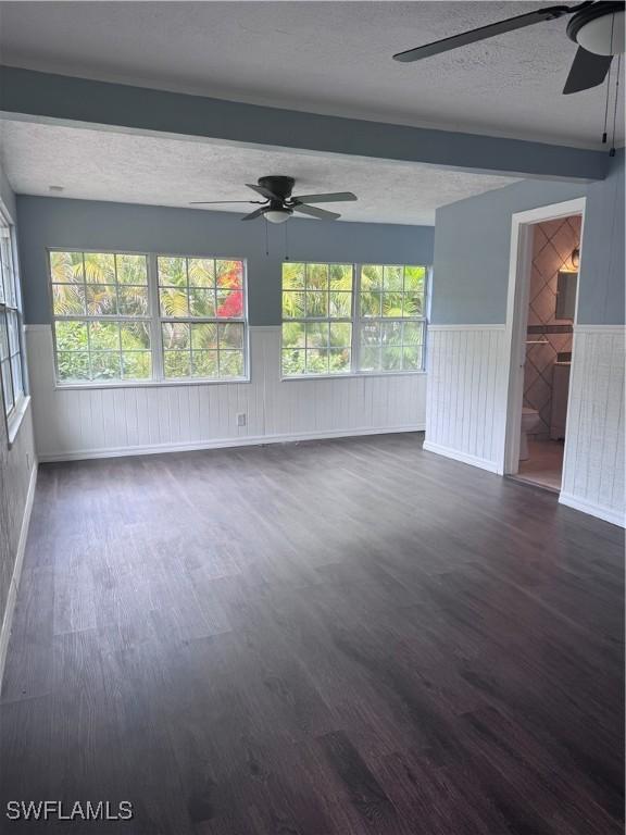 2739 Michigan Ave, Fort Myers, FL 33916 - unfurnished living room featuring a ceiling fan, a textured ceiling, dark wood-type flooring, wainscoting, and beamed ceiling
