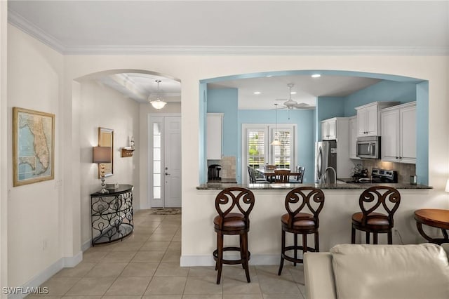kitchen featuring ceiling fan, tasteful backsplash, a kitchen bar, and appliances with stainless steel finishes
