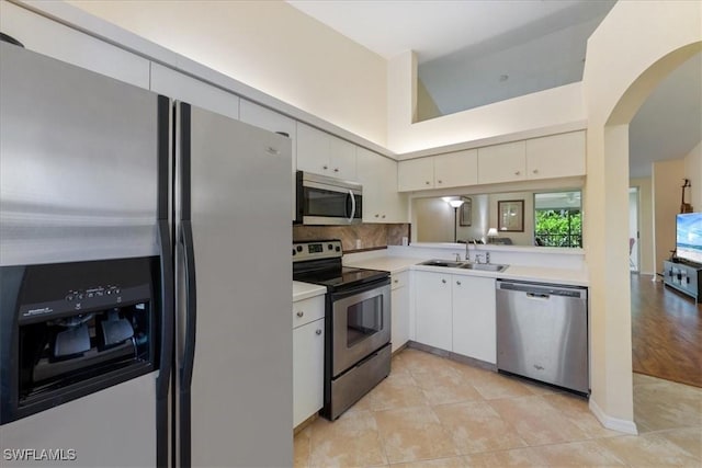 6645 Huntington Lakes Cir Unit 202, Naples, FL 34119 - kitchen featuring white cabinets, appliances with stainless steel finishes, a sink, light countertops, and arched walkways