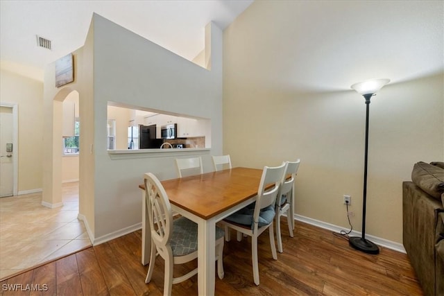 6645 Huntington Lakes Cir Unit 202, Naples, FL 34119 - dining room with arched walkways, baseboards, visible vents, and wood finished floors