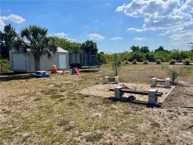 view of yard featuring a trampoline, an outdoor structure, and a shed